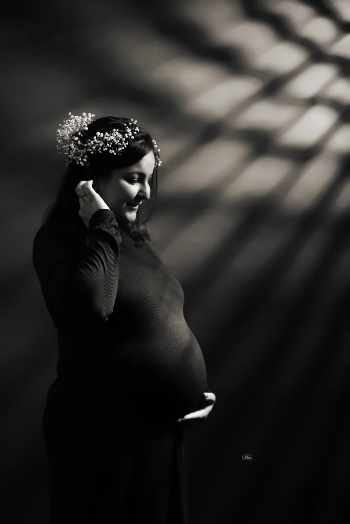 A pregnant woman in black and white with a crown on her head.