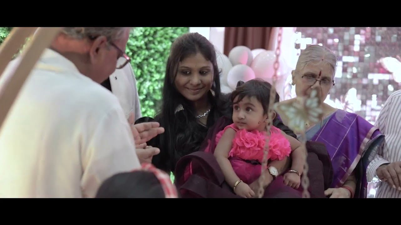 A woman is holding a baby in front of a group of people.
